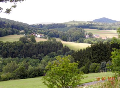 Blick vom Wald zum Bauernhof auf die Auersberge