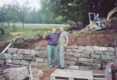 Two good friends pose for a photo in front of the home-made wall